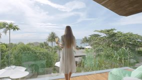 Woman walks to the balcony from luxury villa bedroom - Powered by Shutterstock - Get 15% off with code: PIKWIZARD15