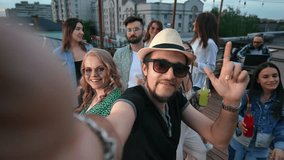 Happy hipster man blog vlog photo selfie at roof party discotheque dancing with friends crowd POV shot. Male influencer shooting video celebration nightclub weekend music entertainment at dancefloor