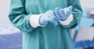 Video of midsection of surgeon wearing surgical gloves and gown in operating theatre. Hospital, medical and healthcare services.