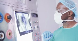 Video of african american male surgeon studying x-ray before operation in operating theatre. Hospital, medical and healthcare services.