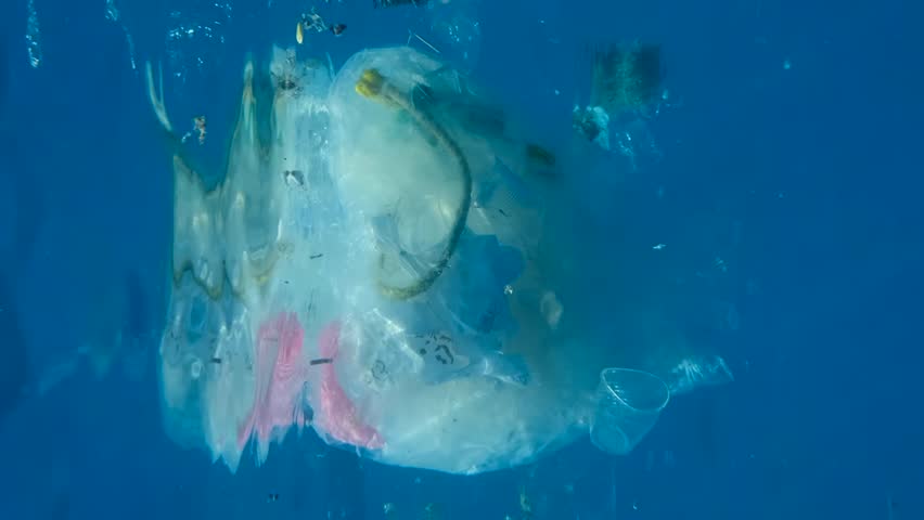 VERTICAL VIDEO, Close-up of a lot of plastic debris slowly drifting under surface of blue water. Plastics bags and cups and other garbage swims underwater. Plastic pollution of Ocean. Slow motion | Shutterstock HD Video #1098578207