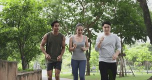 4K video Asian young man and woman jogging together in green park. Concept for healthy lifestyle and outdoor life.