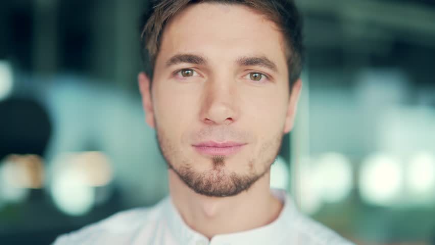 Close-up portrait of young caucasian serious man looking at camera. Head shot Handsome businessman with serene face standing in office. Successful concentrated man employee entrepreneur posing | Shutterstock HD Video #1098590989