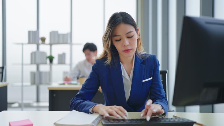 Asian woman employee wearing a suit working and using computer on desk in office | Shutterstock HD Video #1098592441