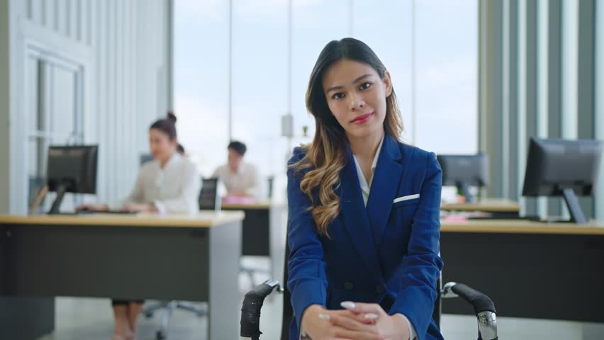 A young Asian businesswoman wearing suit turning chair and looking at the camera at office | Shutterstock HD Video #1098592447