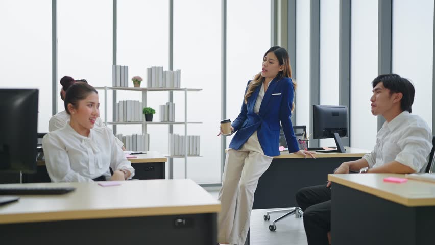 Asian woman manager wearing suit holding a cup of coffee having fun talking with employee in the department at office | Shutterstock HD Video #1098592451
