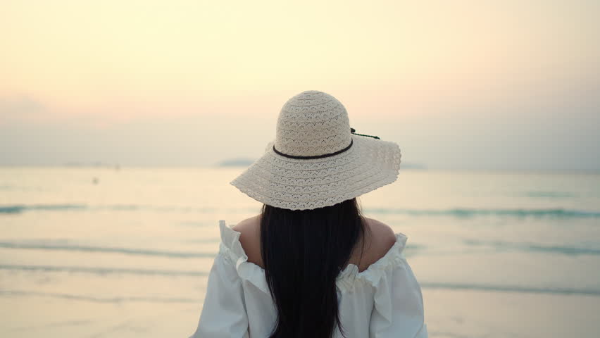 Young Asian woman in white dress walking on the beach while travel tropical island on summer holiday vacation vacation at sunset. Attractive girl relax and enjoy outdoor lifestyle walking at seaside. | Shutterstock HD Video #1098593015