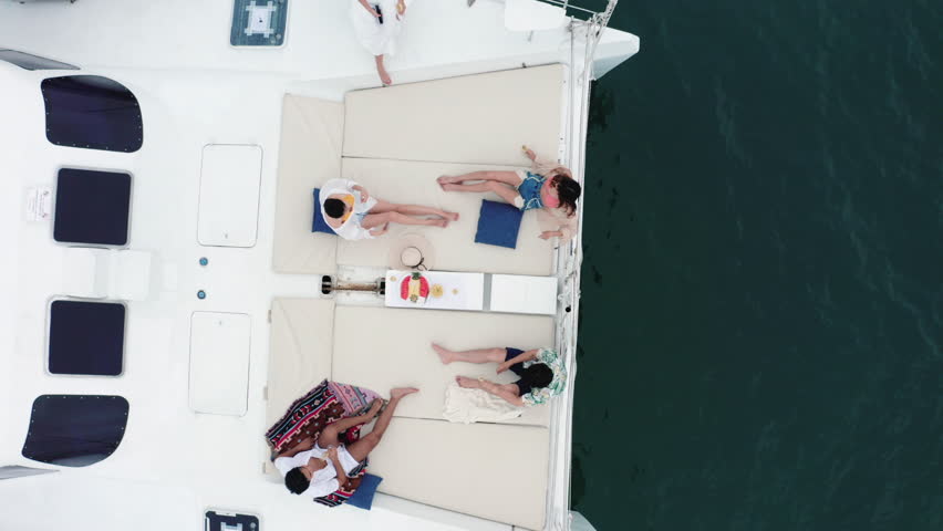 4K Aerial view Group of Asian people friends enjoy outdoor lifestyle celebration party drinking champagne together while travel on luxury catamaran boat yacht sailing in the ocean on summer vacation Royalty-Free Stock Footage #1098593027