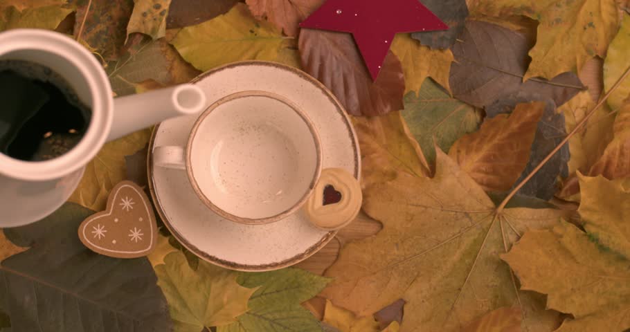 A woman pours coffee into a porcelain cup sitting on the table. Autumn decoration. coffee love.