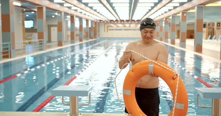 Korean sportsman with lifebelt walk by swimming pool