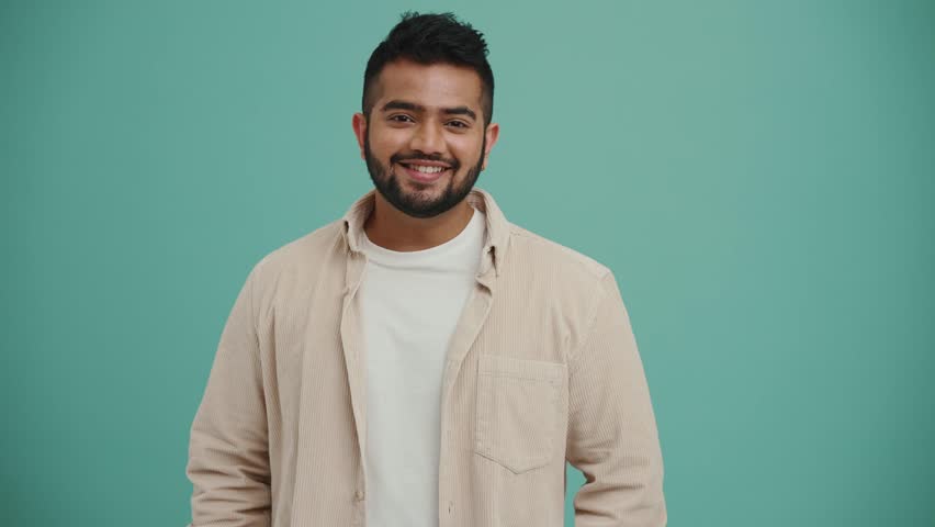 Cheerful Middle Eastern young man looking at the camera in the turquoise studio Royalty-Free Stock Footage #1098600485