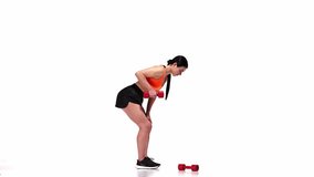 Young sportive girl training over white studio background. Lifting dumbbells. Hands exercises. Workout session. Modern sport, action, motion, youth concept. Fitness, hobby, healthy lifestyle