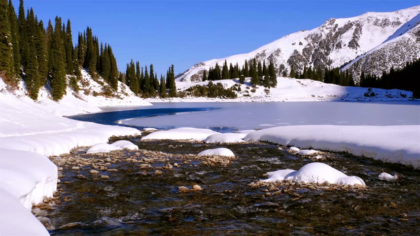 Transparent clean water of a mountain river flows into the lake in the winter season Royalty-Free Stock Footage #1098602523