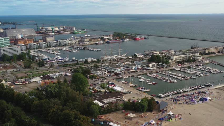 Panning aerial view of seaport in Gydnia Poland with boat dock and beach area