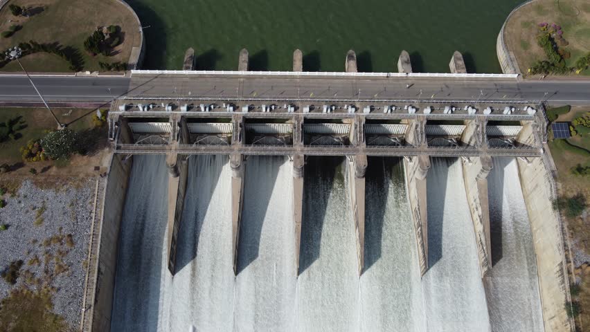 An aerial view over the Pasak Jolasid dam, Lopburi Province, Thailand. Tracking the movement of the floodgates that are releasing water into rural canals in enormous amounts of water. Royalty-Free Stock Footage #1098614811