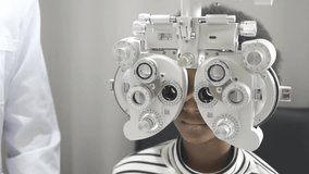 Young African girl doing eye test checking examination with male man optometrist using phoropter in clinic or optical shop. Eyecare concept. - Powered by Shutterstock - Get 15% off with code: PIKWIZARD15