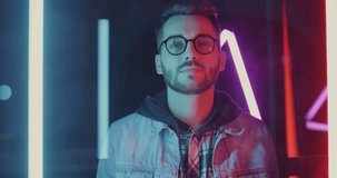 Portrait of young man vlogger speaking and pointing at camera recording video against neon light background. Vlogging and modern lifestyle concept.