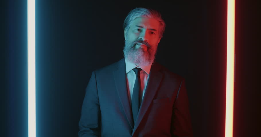 Slow motion portrait of extravagant businessman throwing money and standing on black neon background while cash falling down. People and finance concept.