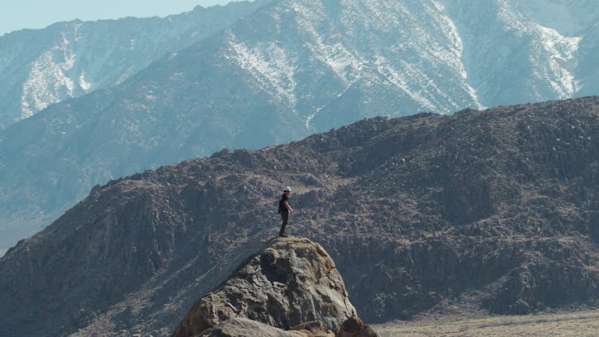 Hiker on top of rocky peak looking at Sierra Nevada mountain range, aerial