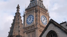 4K close up video with the landmark clock from Big Ben tower in London during a sunny day with blue sky and white clouds through Westminster Parliament