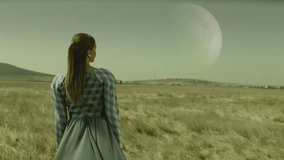Rear view of woman walking on field . Surreal extraterrestrial landscape . Surface of earth with planets in the cloudy sky . Moon at day . Concept of mystic dreams . Approach of two nearby planets