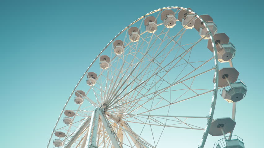 Ferris wheel. Family fun in the amusement park. White ferris wheel rotates against clean blue sky. Close-up of a Ferris wheel with illumination.  Royalty-Free Stock Footage #1098622483