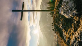 Vertical video of Sunset over steel cross in rocky hill in spring rural nature with fast motion clouds sky Time lapse christian symbol