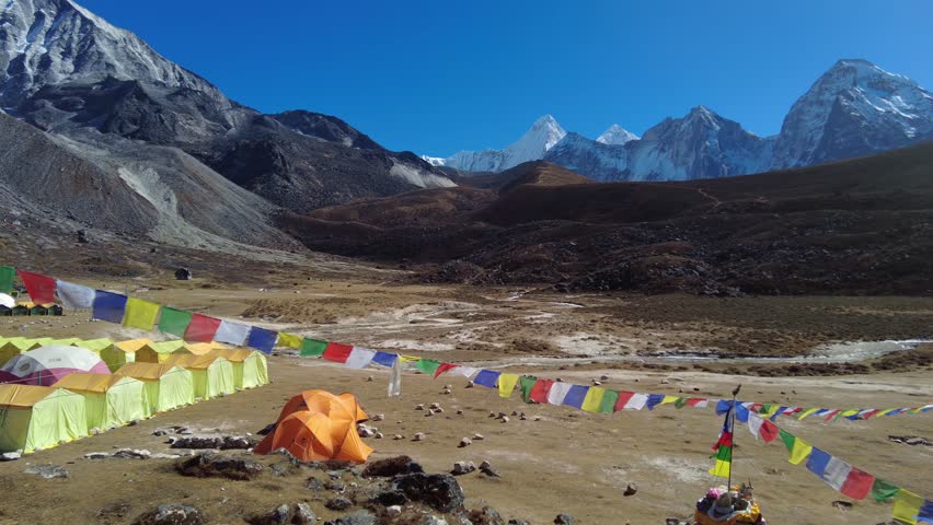 Ama Dablam, Nepal: Tibetan buddhism prayer flags at the Ama Dablam base camp above Pangboche on a sunny winter day in the Himalayas in Nepal. Shot with a pan to the left motion.  Royalty-Free Stock Footage #1098635589