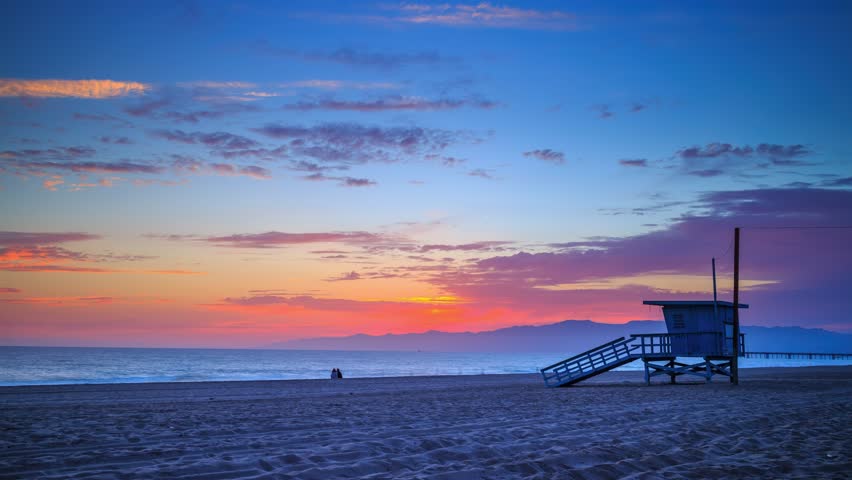 Colorful sunset over ocean in Venice Beach, Santa Monica, Los Angeles, California. Zoom in on lifeguard tower. 4K Timelapse. Royalty-Free Stock Footage #1098641855