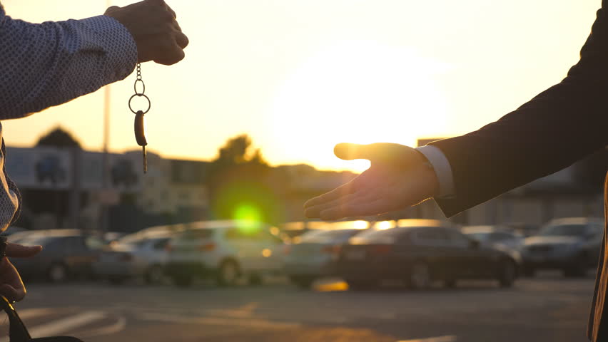 Male hands in suit giving keys of car to his friend. Arm of businessman passes car key. Handshake between two business men outdoor. Close up Slow motion | Shutterstock HD Video #1098644811