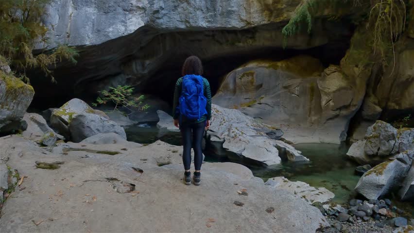 Adventurous woman standing inside a cave. Adventure Travel. Little Huson Caves Park, Vancouver Island, British Columbia, Canada. Slow Motion Cinematic