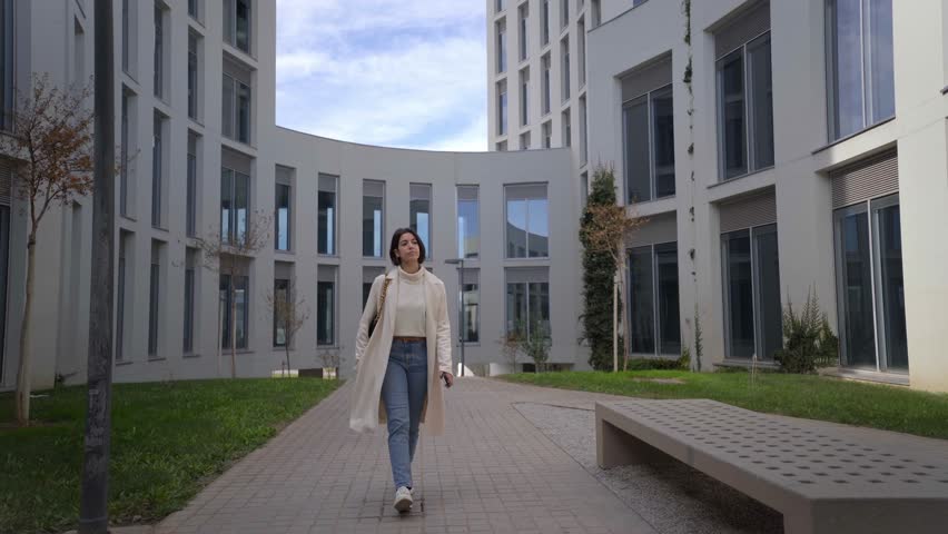 Young business Caucasian woman walking outside, arriving to corporative workplace. Medical center. Full length.