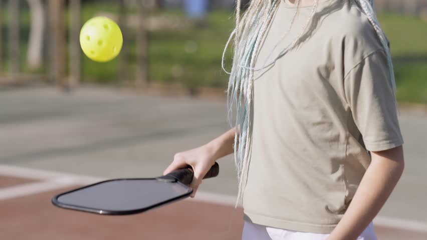 Pickleball paddle and yellow ball close up in children hands, leisure outdoor sport activity. | Shutterstock HD Video #1098649055