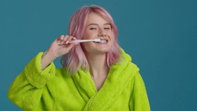 Young woman in neon robe caring about dental hygiene at home in morning slow motion. Deep teeth cleaning. Mirror pov portrait of young hipster girl with pastel pink hair brushing teeth with toothbrush - Powered by Shutterstock - Get 15% off with code: PIKWIZARD15