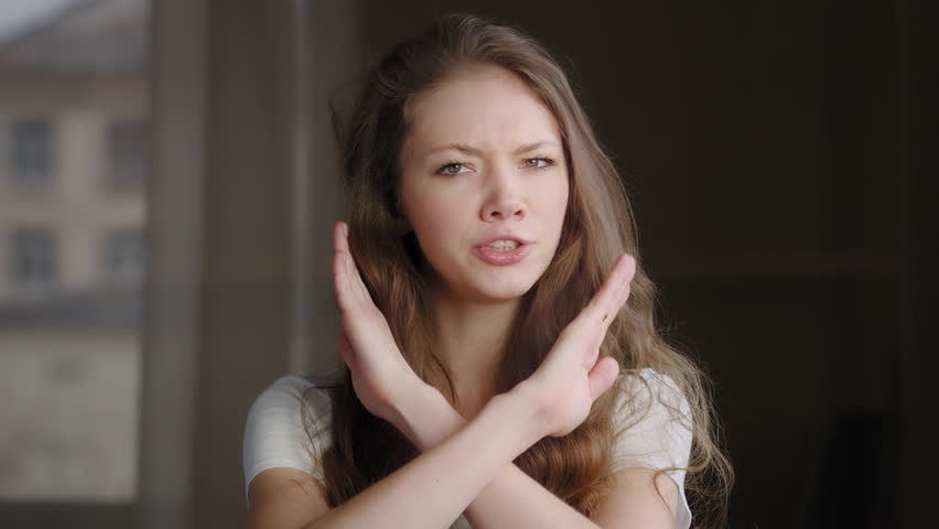 Close-up female portrait young caucasian woman showing prohibition sign crossing arms making refusal gesture negative shaking head dissatisfied serious girl says no refuses demonstrates stop gesture | Shutterstock HD Video #1098651209