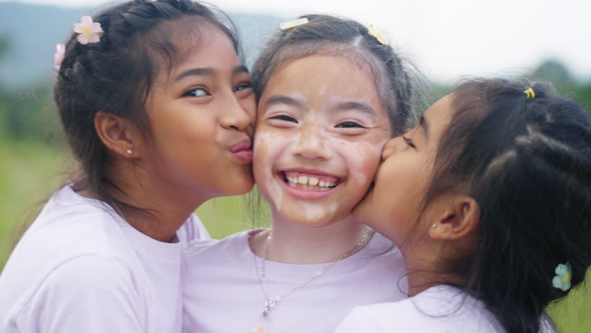 Three little cute child asia sisters kiss cheek cuddle hug look at camera smile fun having good time best friend. Diverse skin sibling Young people small kid girls love trust relax happy sweet moment. | Shutterstock HD Video #1098668429