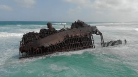 Cabo Santa Maria ship wreck located on the coast of Boa vista island. Old almost fully rusted ship. Drone video of flying around the abandoned wreck which is being smashed by the waves