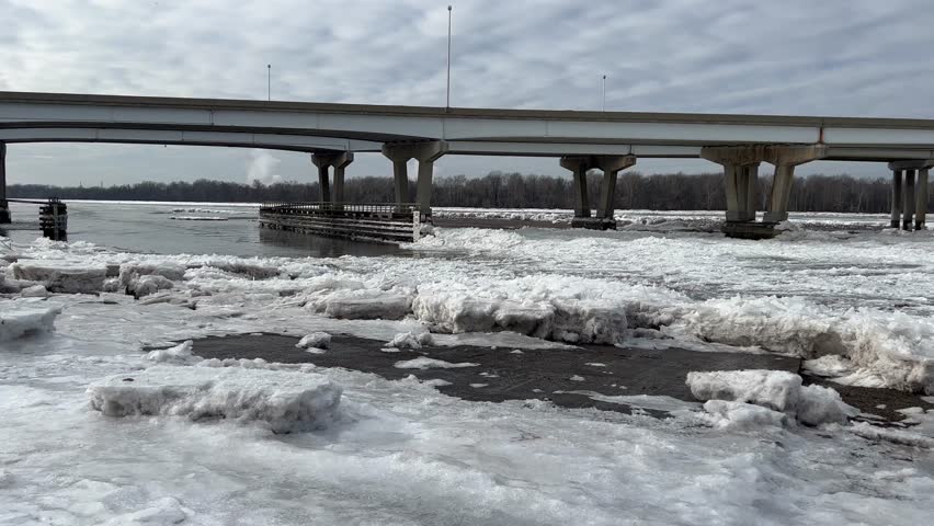 Pan along a long highway bridge that spans over an icy river