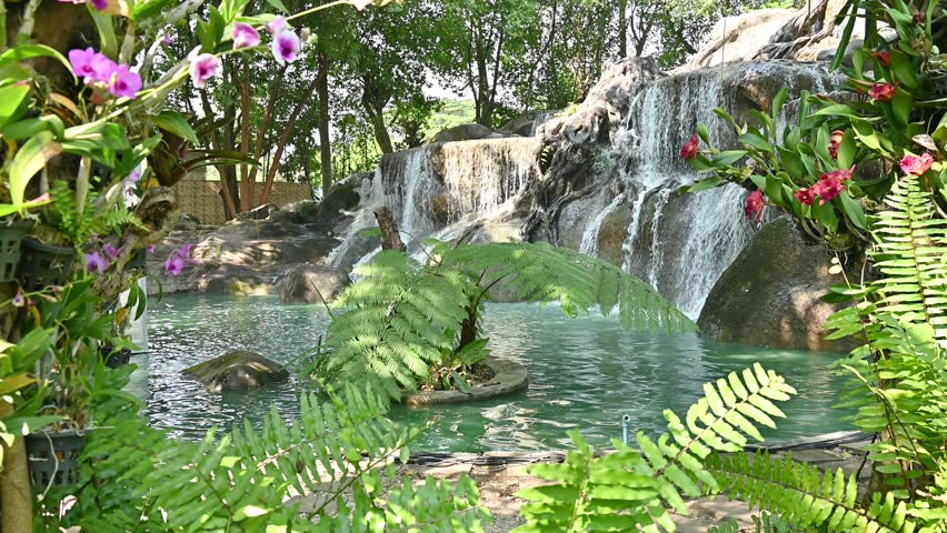 Water flowing from large artificial waterfall in ornamental garden.