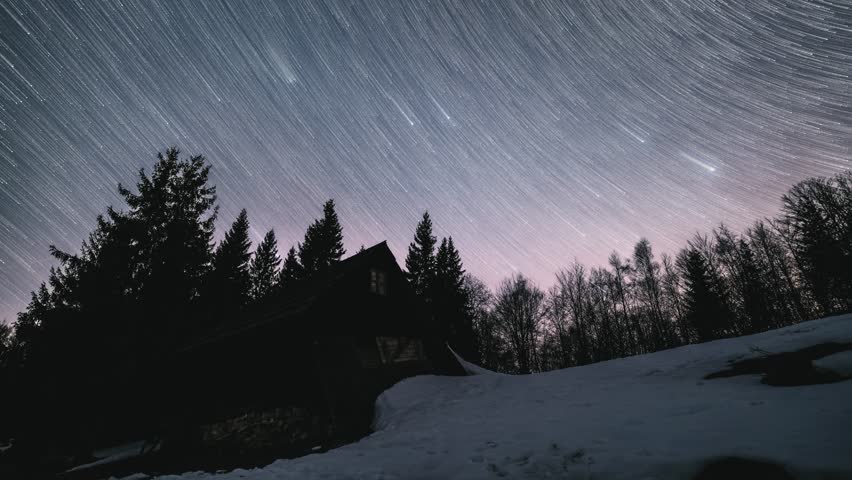 Stars trails motion over wooden hut in wild forest nature in winter starry night sky Astronomy Time lapse
