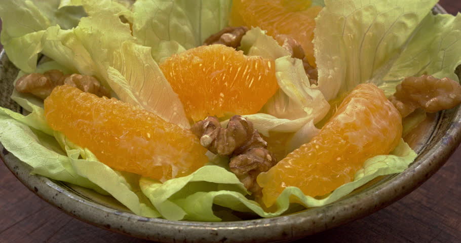 Orange salad with orange fruit, romaine lettuce and walnut nuts. Fresh, homemade salad, table spin. Seamless loop.