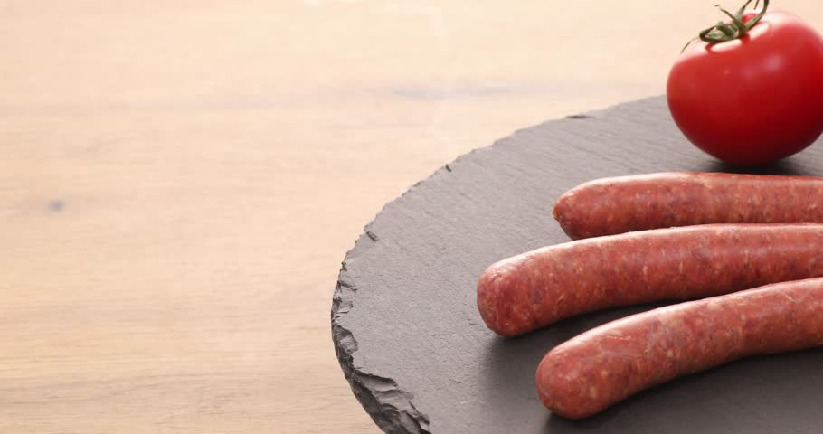  raw sausages on a table with tomato. ready to fry. traditional cuisine. High quality 4k footage