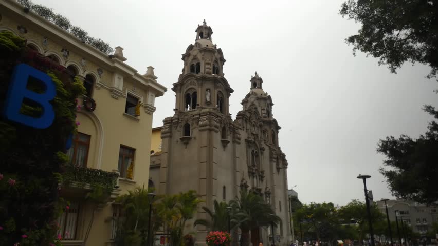 A tall church or cathedral called "Virgen Milagrosa" located in Lima, Peru in the Miraflores district very near to a public park called "Parque Kennedy".