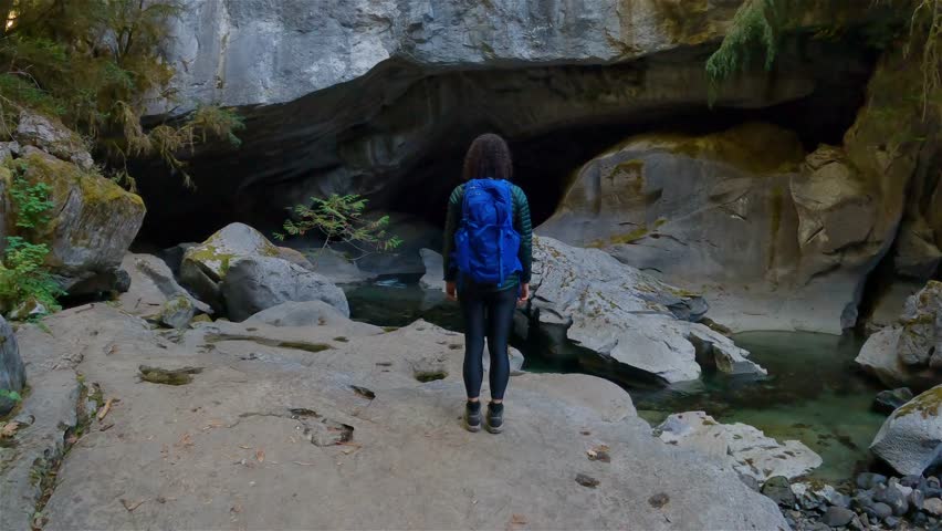 Adventurous woman standing inside a cave. Adventure Travel. Little Huson Caves Park, Vancouver Island, British Columbia, Canada. Slow Motion Cinematic