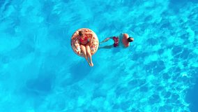 Couple having fun in the pool, the man swims and the woman lies on a donut - Powered by Shutterstock - Get 15% off with code: PIKWIZARD15