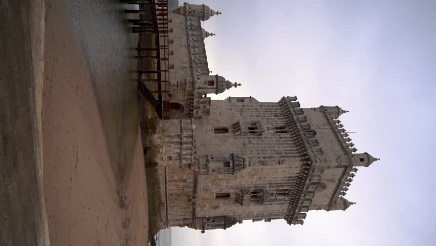Vertical video of an old well preserved portuguese construction in Lisboa with beautiful architecture in the sandy shoreline, Torre de Belem.