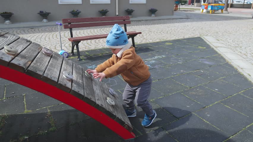 A boy on a playground in an autumn park climbs a hill in cloudy weather