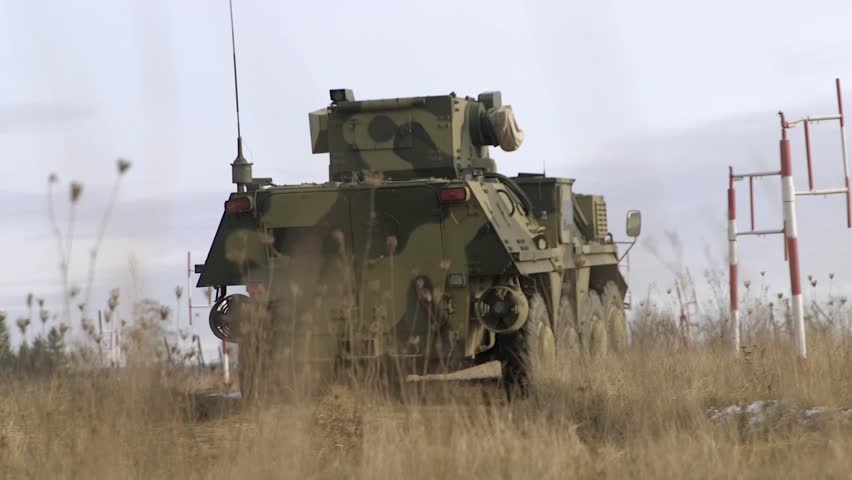 HANDHELD SHOT: Armored car at the post on the road, rear view and side view, close up. Handheld shooting. Close-up of an armored personnel carrier of the Ukrainian army riding on the road. Royalty-Free Stock Footage #1098693323