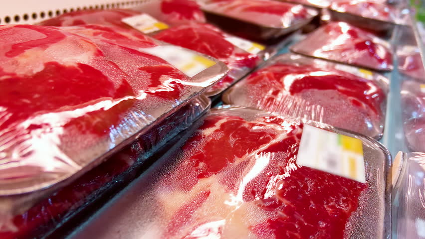 Raw beef fillets or steaks in cling-wrap plastic containers are in a supermarket refrigerator. Close-up shot Royalty-Free Stock Footage #1098693559