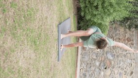 A woman does yoga in the park on the grass, summer stretching training on the street. Vertical Video